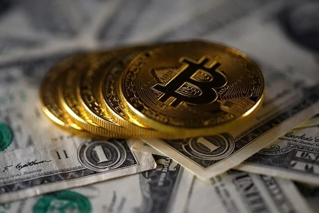 Các đồng xu biểu trưng của Bitcoin được đặt trên nhiều tờ đôla Mỹ. Ảnh: Reuters