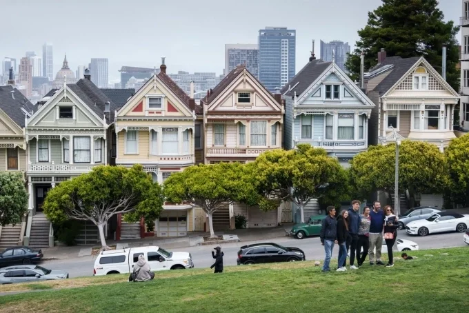 Du khách tạo dáng chụp ảnh trước những ngôi nhà mang phong cách Victoria nổi tiếng ở Quảng trường Alamo, San Francisco. Ảnh: AFP