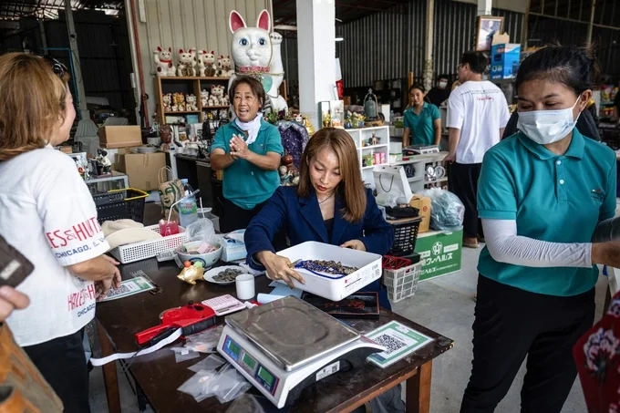 Chủ tiệm Wipaporn Je Nana Sakdisakwasdi cân đồ trang sức cho khách trong cửa hàng bán hàng bãi Nhật Bản của cô tại Nonthaburi, ngoại ô Bangkok, ngày 30/5. Ảnh: AFP