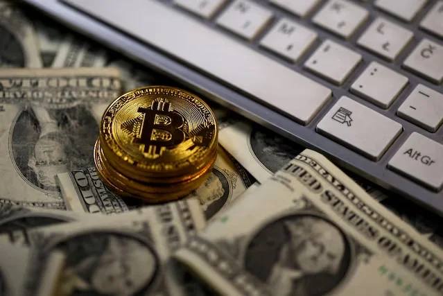 Các đồng xu biểu trưng của Bitcoin được đặt trên tờ đôla Mỹ. Ảnh: Reuters