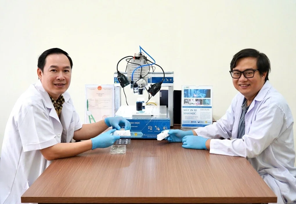 PGS.TS Nguyễn Ngọc Đỉnh (phải), đồng chủ nhiệm và PGS.BS.TS Đỗ Xuân Hai, thành viên chính dự án và hệ máy in 3D sinh học sử dụng mực in tế bào gốc. Ảnh: VNU