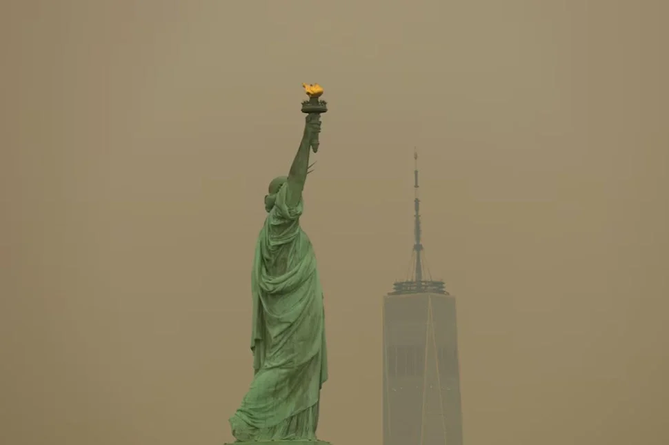 Tượng Nữ thần Tự do tại bến cảng New York nhìn qua làn khói cháy rừng dàyact ở thành phố Jersey, bang New Jersey, Mỹ, ngày 16/7. Ảnh: Reuters/Mike Segar