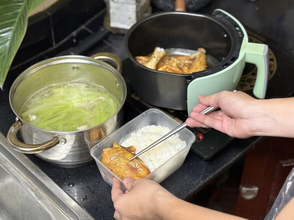 Do lỡ nấu nhiều, một người đàn ông ở phường Giảng Võ, Hà Nội, đóng hộp phần cơm gà, canh bí thịt băm, sau đăng bài lên nhóm tìm người nhận, tối 14/7. Ảnh: Hoài Thương